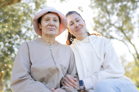 Senior woman with pink hat and her daughter enjoying sunny day in park