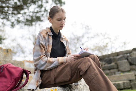 Young woman writing outdoors in archaeological site