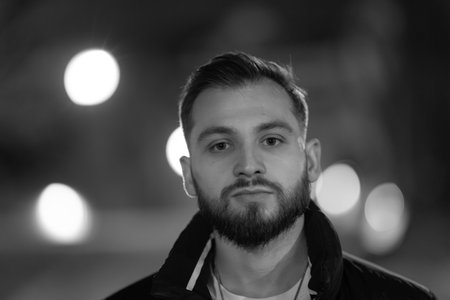 Young bearded man posing confidently in dark city