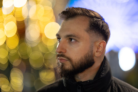 Young man looking up at glowing city lightsの写真素材