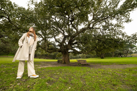 Woman enjoying nature walking in park looking up