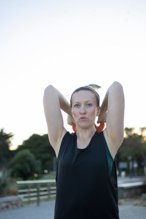 Woman exercising outdoors doing triceps extension with kettlebell