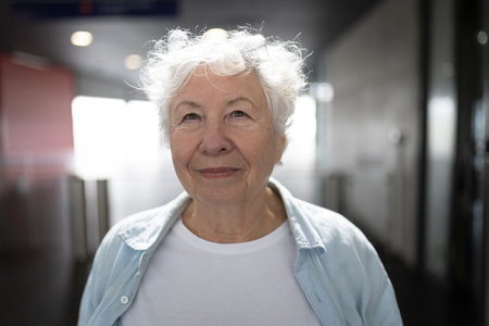 Portrait of smiling senior woman with white hair in corridorの写真素材
