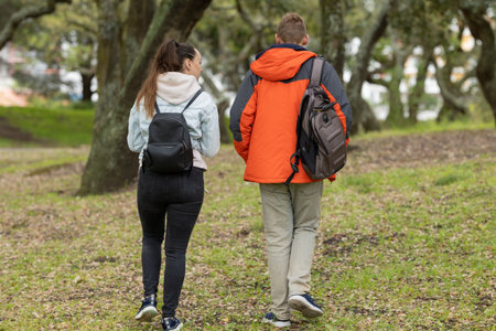 Young couple walking away outdoors carrying backpacks