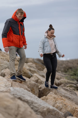 Couple walking carefully on rocks exploring outdoor nature