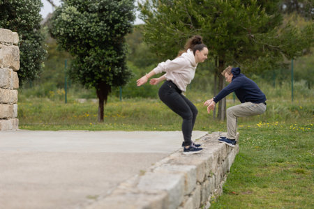 Young couple jumping over stone wall outdoorsの写真素材