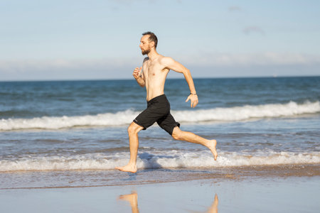 Man running on a summer ocean beachの写真素材