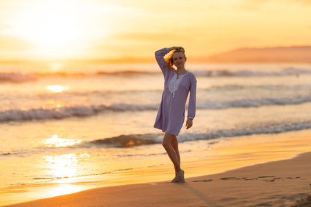 Woman enjoying golden sunset on sandy beachの写真素材