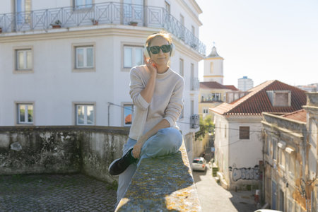 Woman enjoying music in headphones on city wallの写真素材