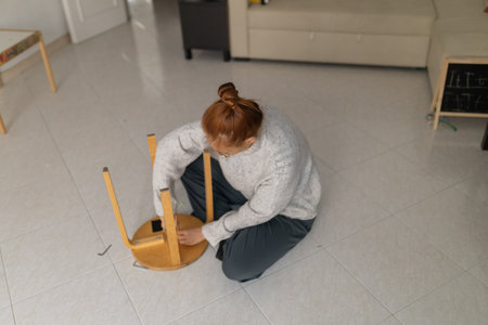 Woman assembling wooden furniture stool at home