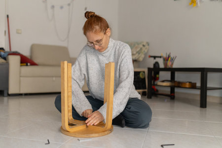 Woman assembling wooden furniture stool with hex key in living room
