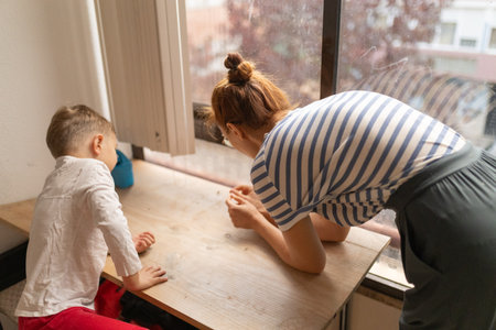 Mother and child observing outside view from windowの写真素材
