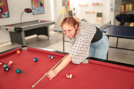 Woman playing billiards concentrating on pool cue shot