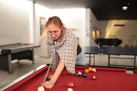 Woman playing billiards in game room