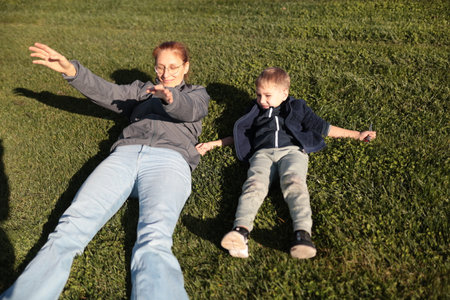 Mother and child holding hands relaxing on grass