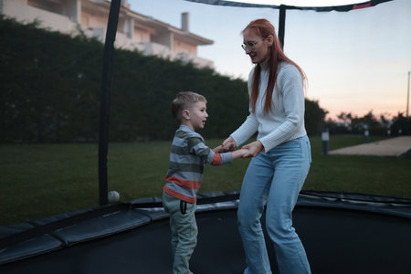 Mother and son having fun jumping on trampolineの写真素材