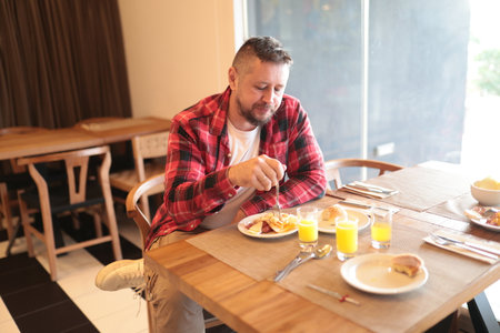 Man enjoying hotel breakfast eating a full mealの写真素材