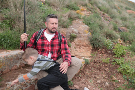 Father and son exploring nature on hillsideの写真素材