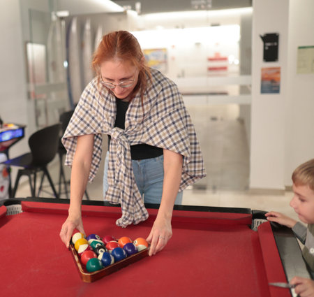 Woman racking billiard balls teaching child game