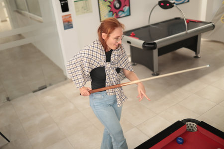 Woman playing billiards in game room concentrating on shot