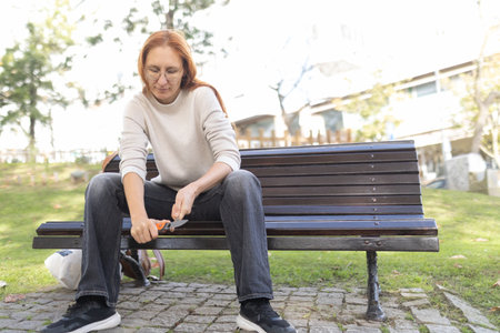 Woman holding knife sitting on a park benchの写真素材