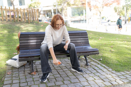 Woman opening box with utility knife on park benchの写真素材