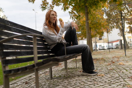 Woman with red hair enjoying apple in urban park