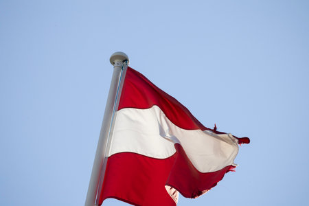 Austrian flag waving in wind against blue skyの写真素材