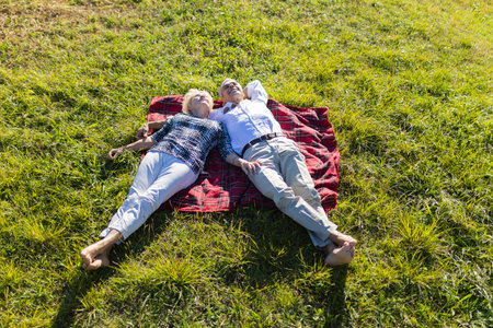 Senior couple enjoying peaceful relaxation lying on grass