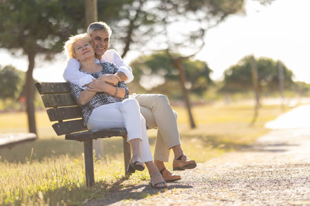 Senior couple embracing on park bench enjoying retirementの写真素材