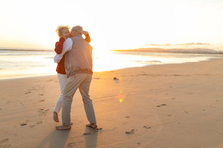 Senior couple embracing on beach at beautiful sunset