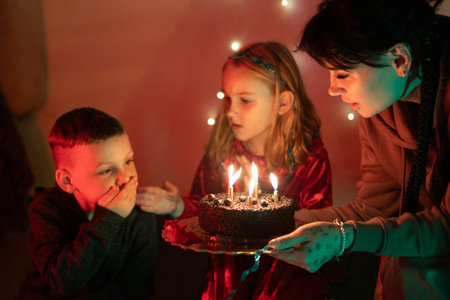 Family celebrating birthday with chocolate cake and candlesの写真素材