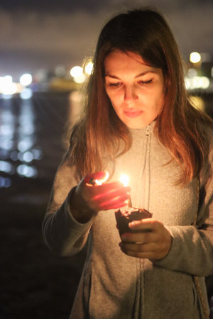 Woman holding burning candle expressing hope and memoryの写真素材