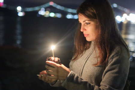 Woman holding cupcake with lit candleの写真素材