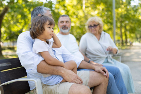 Multi-generational family sitting on park bench enjoying outdoor timeの写真素材