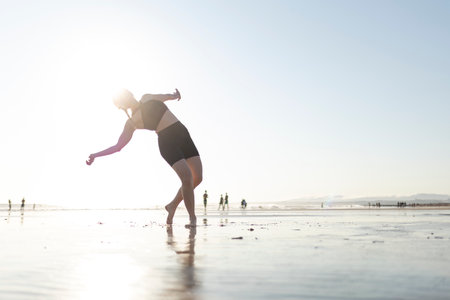 Woman practicing expressive dance on ocean beachの写真素材