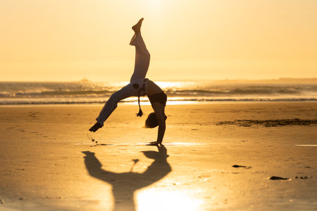 Capoeira artist performing on beach during sunsetの写真素材