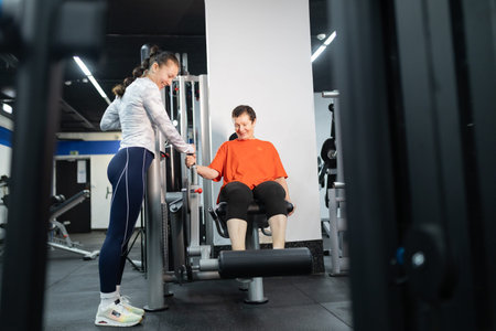 Personal trainer guiding senior woman doing leg exercise