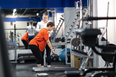 Personal trainer guiding woman exercising in modern gym