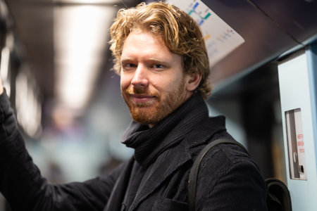 Young man riding subway train smiling, commuting dailyの写真素材