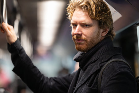 Young man commuting on urban public transport holding railの写真素材