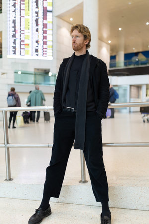 Man in black outfit standing in airport terminalの写真素材