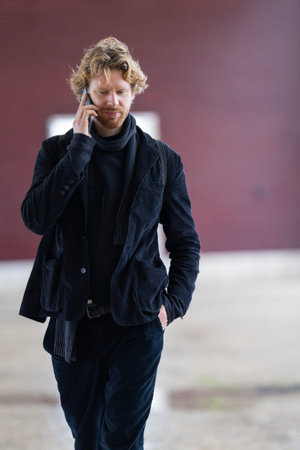 Young man walking and talking on mobile phoneの写真素材