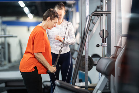 Senior woman training with personal trainer at gymの写真素材