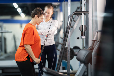 Senior woman training with personal coach strengthening arm muscles