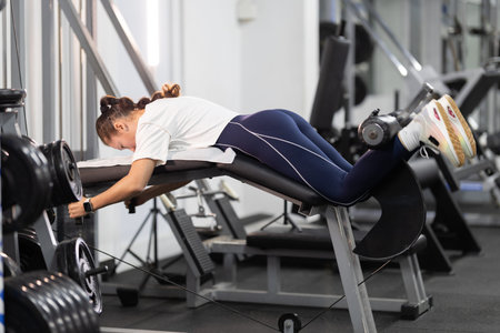 Woman exercising hamstrings on leg curl machine in a gym