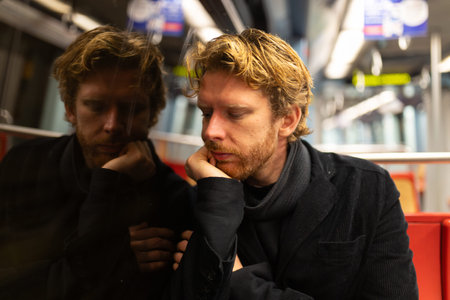 Tired man commuting on public transport looking pensiveの写真素材