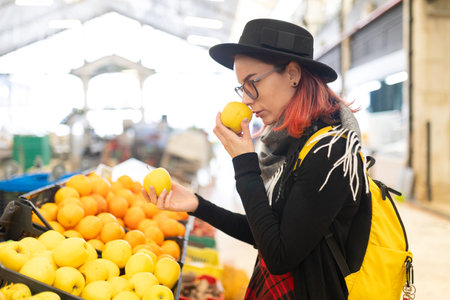 Woman smelling fresh yellow apple at marketの写真素材