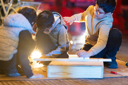Children learning woodworking together in a creative workshopの写真素材