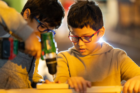 Young boys learning carpentry skills using a power drill